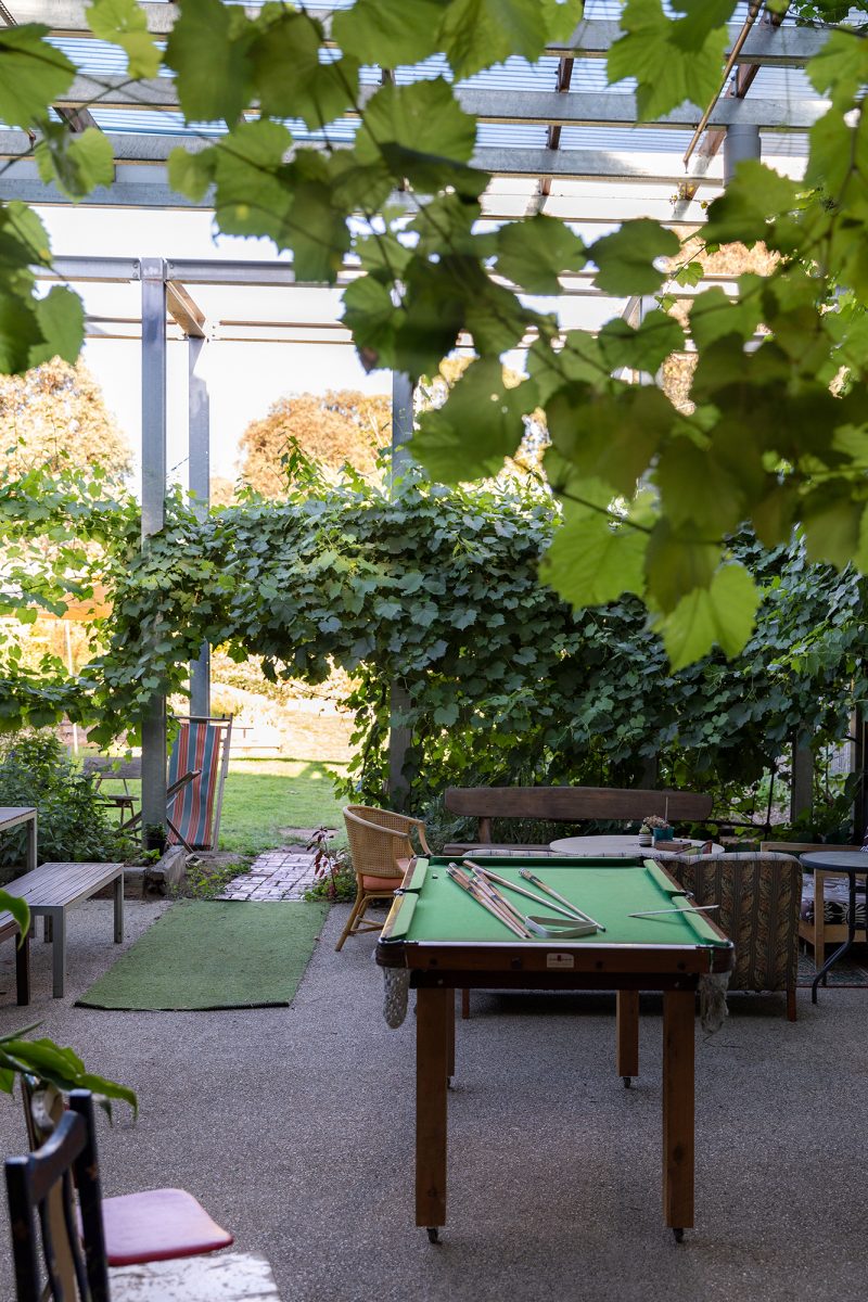 Housing Co-operative Murundaka showcases how transformative change is possible in the suburbs of Melbourne | Pool table amongst green vines and plants in a communal area | Co-op living Australia | cohousing collective | Photography by Jasmine Fisher | edited by Jana Perković | Assemble Papers