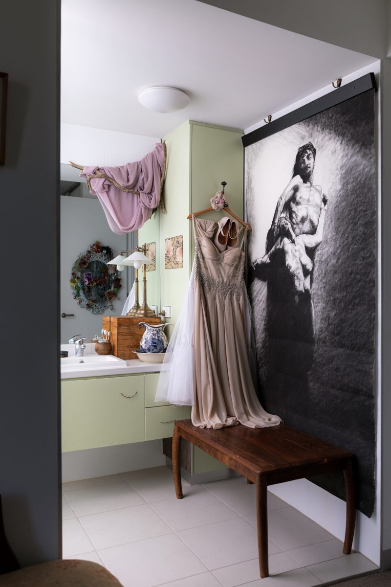 Housing Co-operative Murundaka showcases how transformative change is possible in the suburbs of Melbourne | Green bathroom with hanging ball gown dresses and wooden table| Co-op living Australia | cohousing collective | Photography by Jasmine Fisher | edited by Jana Perković | Assemble Papers
