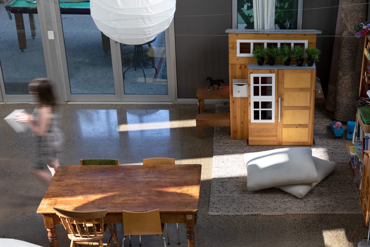 Housing Co-operative Murundaka showcases how transformative change is possible in the suburbs of Melbourne | Large common house room with grey floor cushions, wooden tables and chairs, book shelves and polished concrete flooring | Co-op living Australia | cohousing collective | Photography by Jasmine Fisher | edited by Jana Perković | Assemble Papers