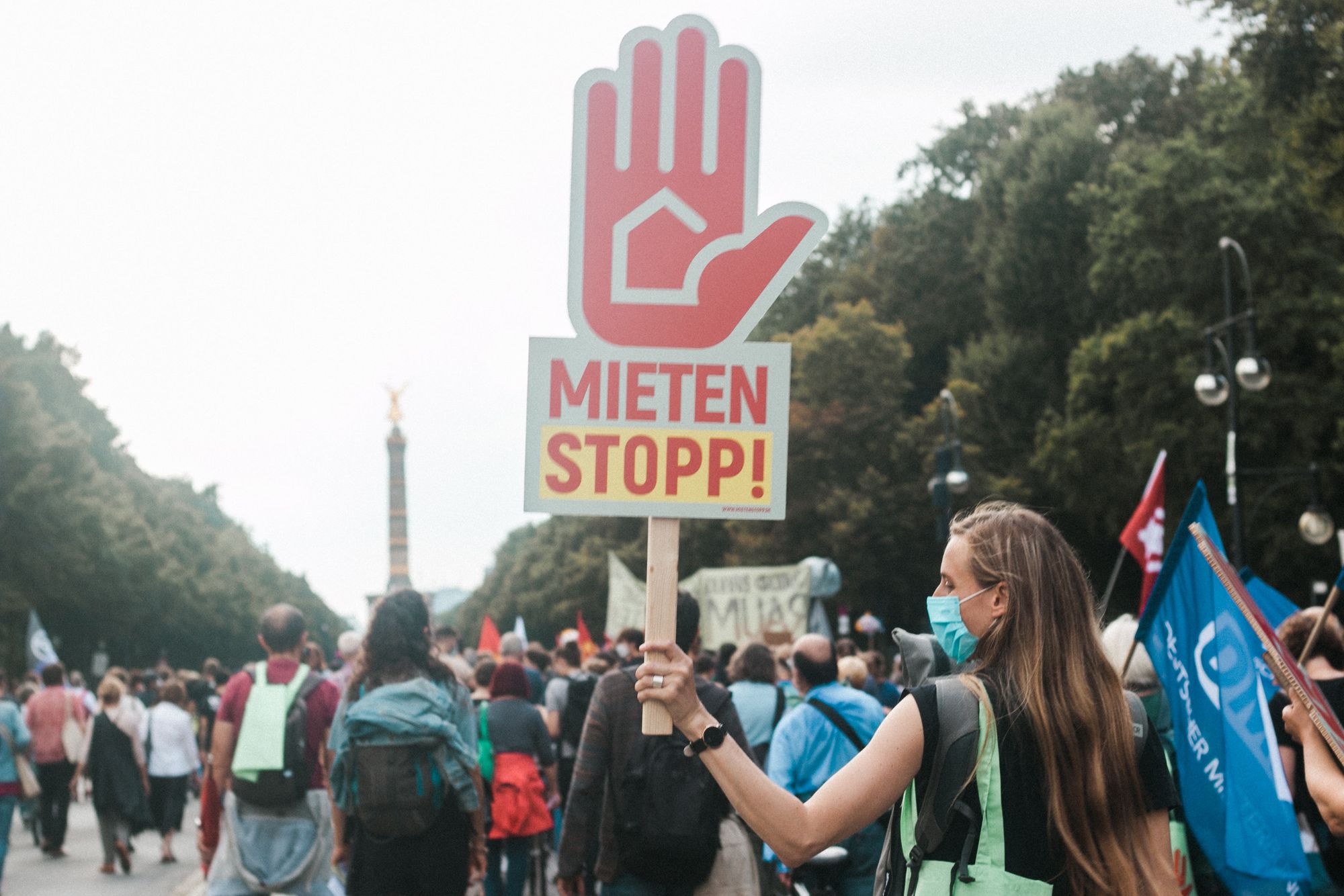 At a protest in Berlin, a woman holds up a sign in the shape of a hand with the words saying Meiten Stopp!