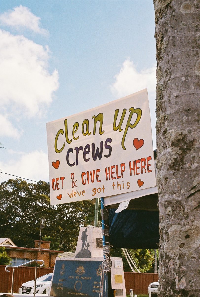 A hand-drawn side outside Mullumbimby Memorial Hall says Çlean up crews - get and give help here'in bright colours. The sign is also decorated with love hearts.